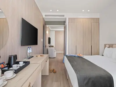 a bedroom with a bed and a tv on a wall at Mercure Larnaca Finikoudes Beach in Larnaka