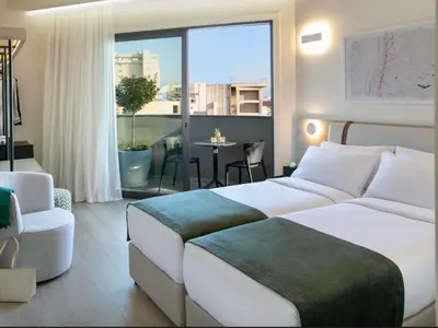 a hotel room with a bed and a large window at Mercure Larnaca Finikoudes Beach in Larnaka