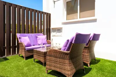 a patio with wicker chairs and a table with purple cushions at Villa Cypriana in Protaras
