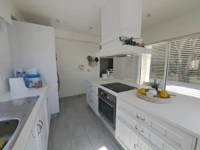 a white kitchen with a sink and a stove at Sandy Coast Beach Villa in Larnaka