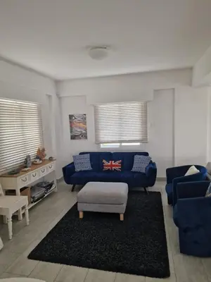 a living room with a blue couch and a table at Sandy Coast Beach Villa in Larnaka