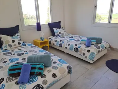 a room with two beds and two chairs in it at Sandy Coast Beach Villa in Larnaka