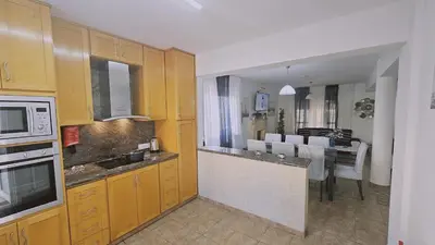 a kitchen with wooden cabinets and a dining room at STAY Princess Villa in Protaras