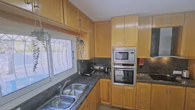a kitchen with wooden cabinets and a sink and a window at STAY Princess Villa in Protaras