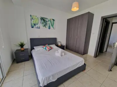 a bedroom with a bed with white sheets and pillows at Tropical Paradise 200m from Finikoudes beach in Larnaka