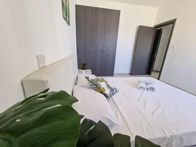 a white bed in a room with a plant at Tropical Paradise 200m from Finikoudes beach in Larnaka