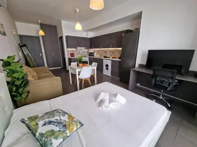 a living room with a white table and a kitchen at Tropical Paradise 200m from Finikoudes beach in Larnaka