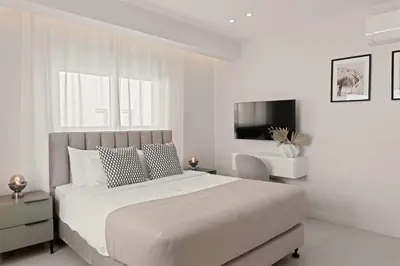 a white bedroom with a large bed and a tv at Phaedrus Living: Limassol Seaside Residences 05 in Limassol