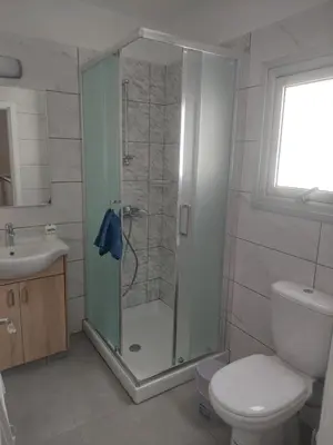 a bathroom with a shower with a toilet and a sink at Green Bay Suites in Protaras