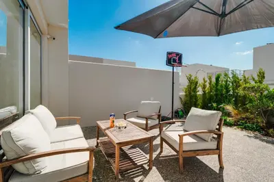a patio with two chairs and a table and an umbrella at NEW 2BR Townhouse in Luxury Resort Pool & Beach in Protaras