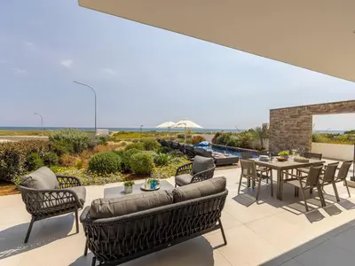 a patio with chairs and a table with a view of the ocean at Villa Pliades in Ayia Napa