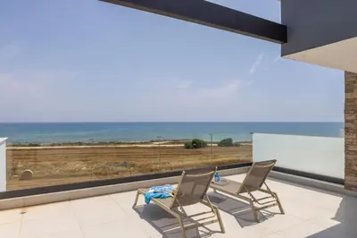 two chairs and a table on a balcony with a view of the ocean at Villa Pliades in Ayia Napa