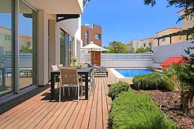 a wooden deck with a table and chairs next to a pool at Villa Sunrise Glory - 150m from Trinity Beach in Protaras