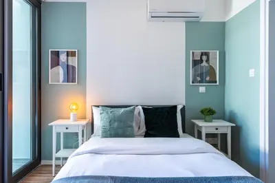 a bedroom with a bed with two tables and two pictures at Arion 1-Bedroom Apartment in Larnaca in Larnaka