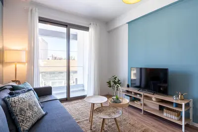 a living room with a blue couch and a large window at Hue 1-Bedroom Apartment in Larnaca in Larnaka