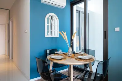 a dining room with blue walls and a table with chairs at Hue 1-Bedroom Apartment in Larnaca in Larnaka