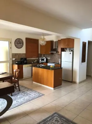 a large kitchen with wooden cabinets and a refrigerator at Budget Escape to the seaside in Larnaka