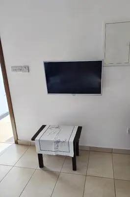 a room with a bench with a flat screen tv on the wall at Mariam Apartment in Larnaka