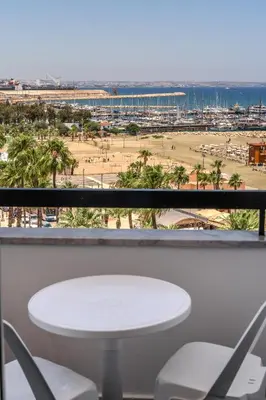 a table and chairs on a balcony with a view of the beach at Finikoudes Seaview Vibe 1 Bdr Flat in Larnaka