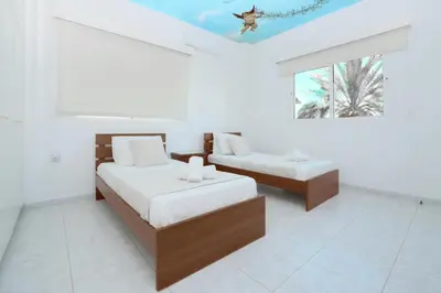 a white room with two beds and a window at Villa Chloe in Ayia Napa