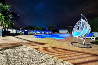 a resort swimming pool with a rattan chair next to it at Villa Chloe in Ayia Napa
