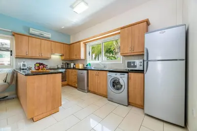 a kitchen with wooden cabinets and a white refrigerator at Pernera Blue Villa in Protaras