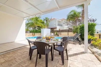 a patio with a table and chairs and a pool at Pernera Blue Villa in Protaras