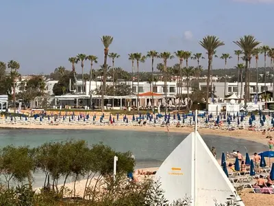a sail boat on a beach with chairs and palm trees at Kritamo Beach Hotel Apartments in Ayia Napa