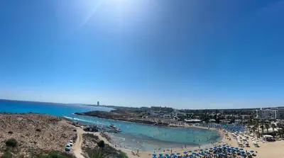 a beach with a bunch of umbrellas and the ocean at Kritamo Beach Hotel Apartments in Ayia Napa