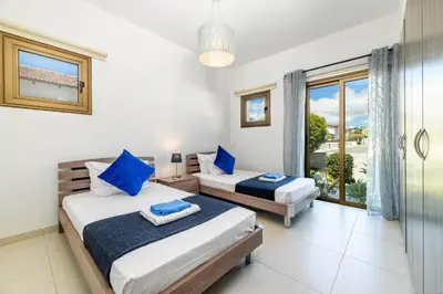 a bedroom with two beds and a window with a view at Kymma Bungalow #2 in Ayia Napa
