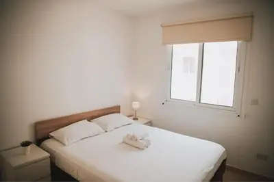 a bedroom with a white bed with a window at Mercury Apartment in Livadhia