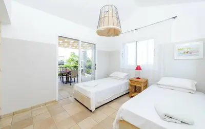 two beds in a white room with a table at Villa Marilena in Protaras