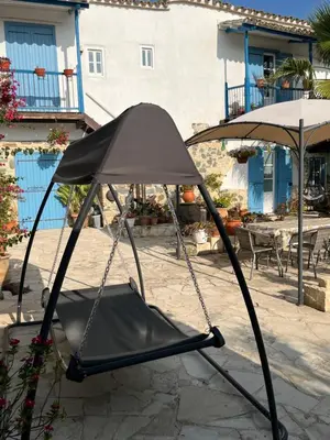 a swing chair in a patio with an umbrella at Traditional House in Pera in Pera