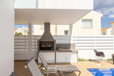 a patio with two chairs and a fireplace at The Second Diamond Protara - 2' Walk to Beach in Protaras