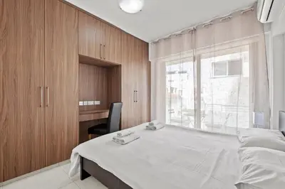 a bedroom with a bed with a chair and a window at Downtown 2 Bedroom Apartment in Larnaka