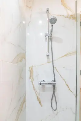 a shower with a shower head on a marble wall at Earth Apartment in Larnaka