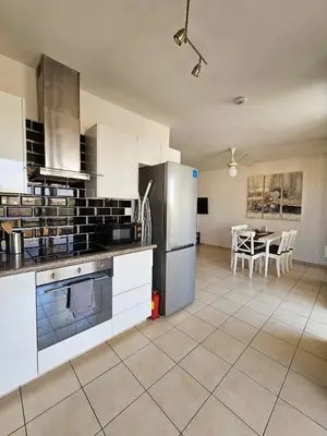 a kitchen with white appliances and a table with chairs at Mediterranean Sunrise Apartments A1 in Voroklini