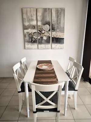 a white dining room table with chairs and a painting at Mediterranean Sunrise Apartments A1 in Voroklini