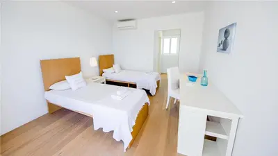 a white room with two beds and a table at Protaras Holiday Villa 100 in Protaras