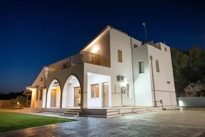 a large white building with a balcony at night at Konnos Villa 1 in Protaras