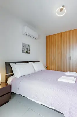 a bedroom with a large white bed and a wooden cabinet at Stylish One-Bedroom Sea Retreat in Paralimni