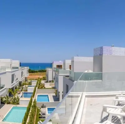 arial view of a building with a pool and the ocean at By the beach Villa 2 in Protaras