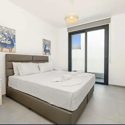 a bedroom with a large bed with a large window at By the beach Villa 2 in Protaras