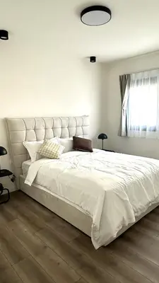 a bedroom with a large white bed with a large headboard at Sunset Gardens - Holiday Apartments in Limassol
