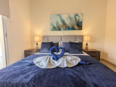 a bedroom with a bed with blue sheets and blue pillows at Violetta Apartment, Ground Floor Pool View in Paralimni