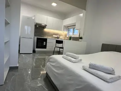 a bedroom with a white bed and a kitchen at Appartments 750m from beach, tourist area in Limassol