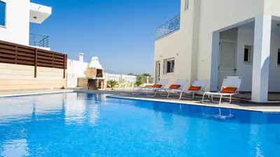 a swimming pool with chairs next to a building at Protaras Holiday Villa 196 in Protaras