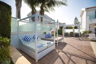 a white canopy bed with blue pillows on a patio at Protaras Holiday Villa 113 in Protaras