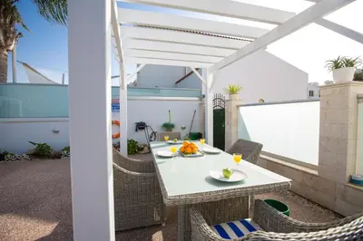 a table and chairs on a patio with a white umbrella at Protaras Holiday Villa 113 in Protaras