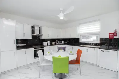 a kitchen with white cabinets and a table and chairs at Protaras Holiday Villa 113 in Protaras